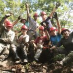 Group of trail crew members posing and raising their arms in celebration